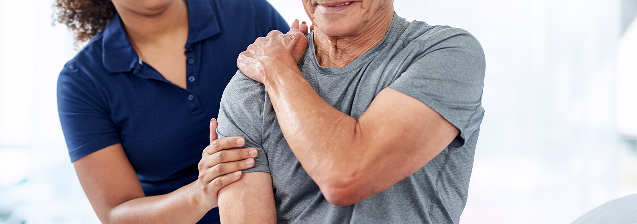 Physiotherapeutin bei der Arbeit mit einem Patienten mit Schulterinstabilität.