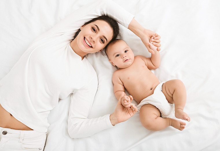 Une mère et son bébé sont allongés sur un lit blanc